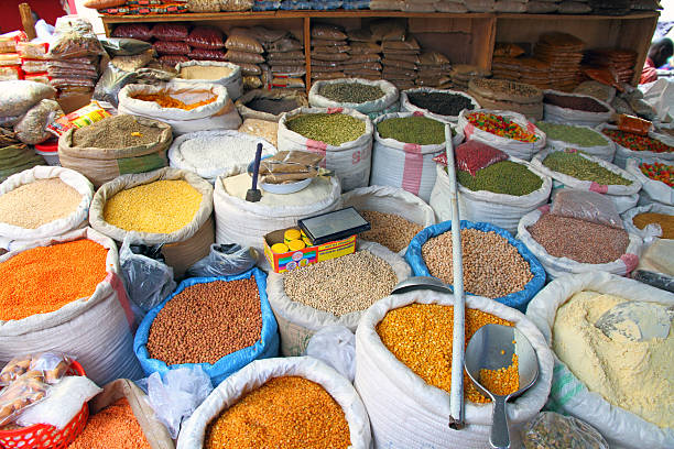 Bags of food staples in an open air market in Kampala, Uganda.  Seen are beans, buts, grains, corn, spices, pastas, sugar, rice.